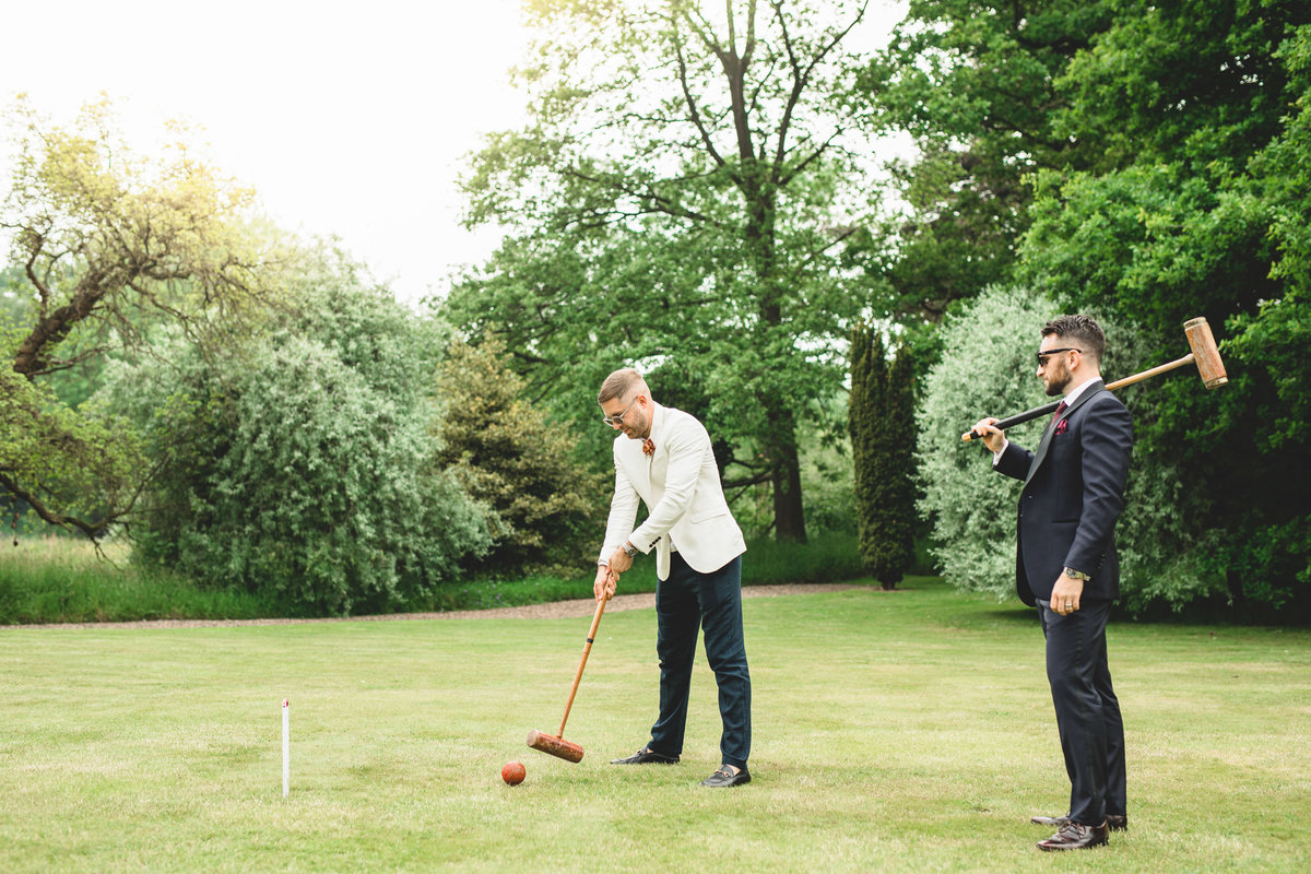 two wedding guests are playing croquet on the lawn at the back of the manor
