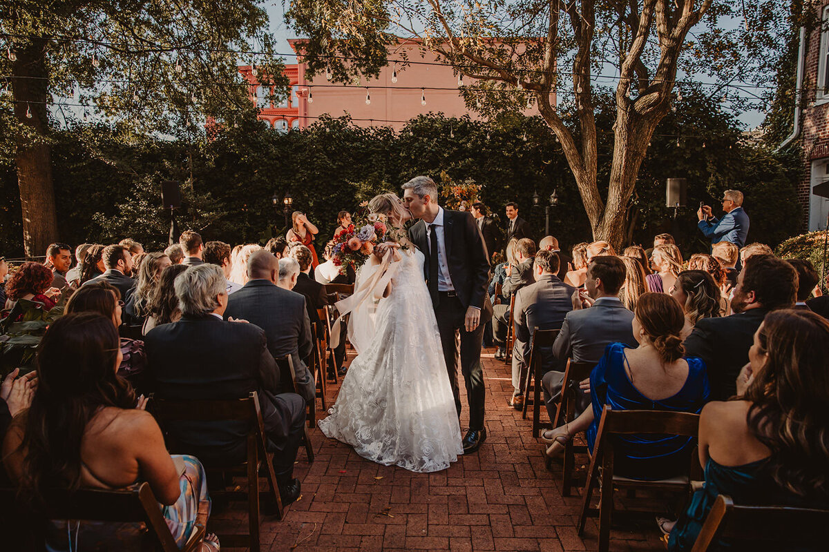 A couple kissing in the middle of the aisle after their wedding ceremony 