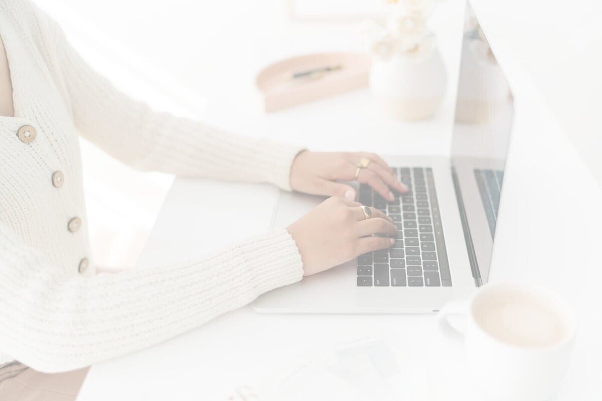 Woman sitting at desk working on laptop, focused on website design and online course creation