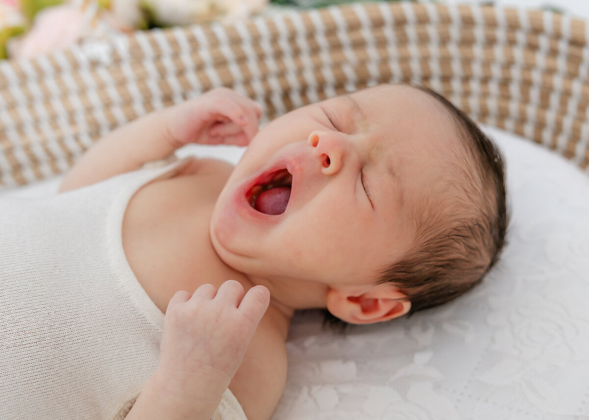 Light and airy photo of newborn baby yawning at Allison Reilly's Union County, NJ photo studio.