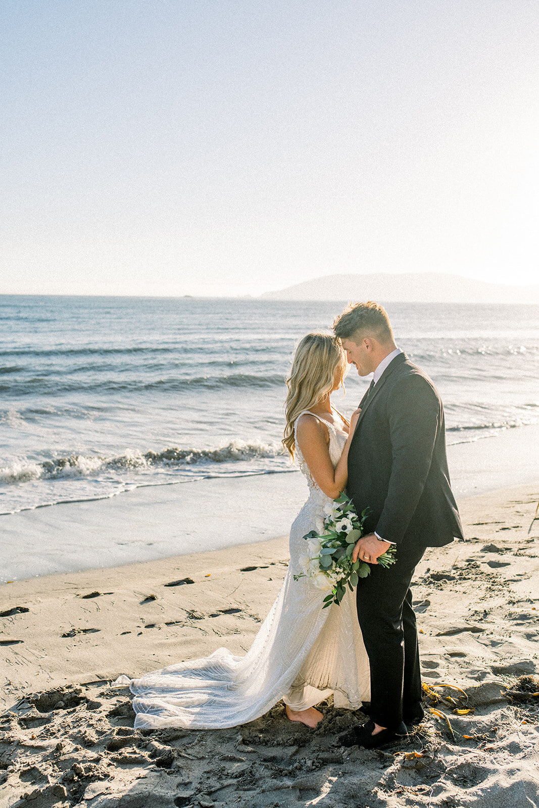 Bride and groom walking on the beach at Dolphin Bay Resort in Pismo Beach, CA