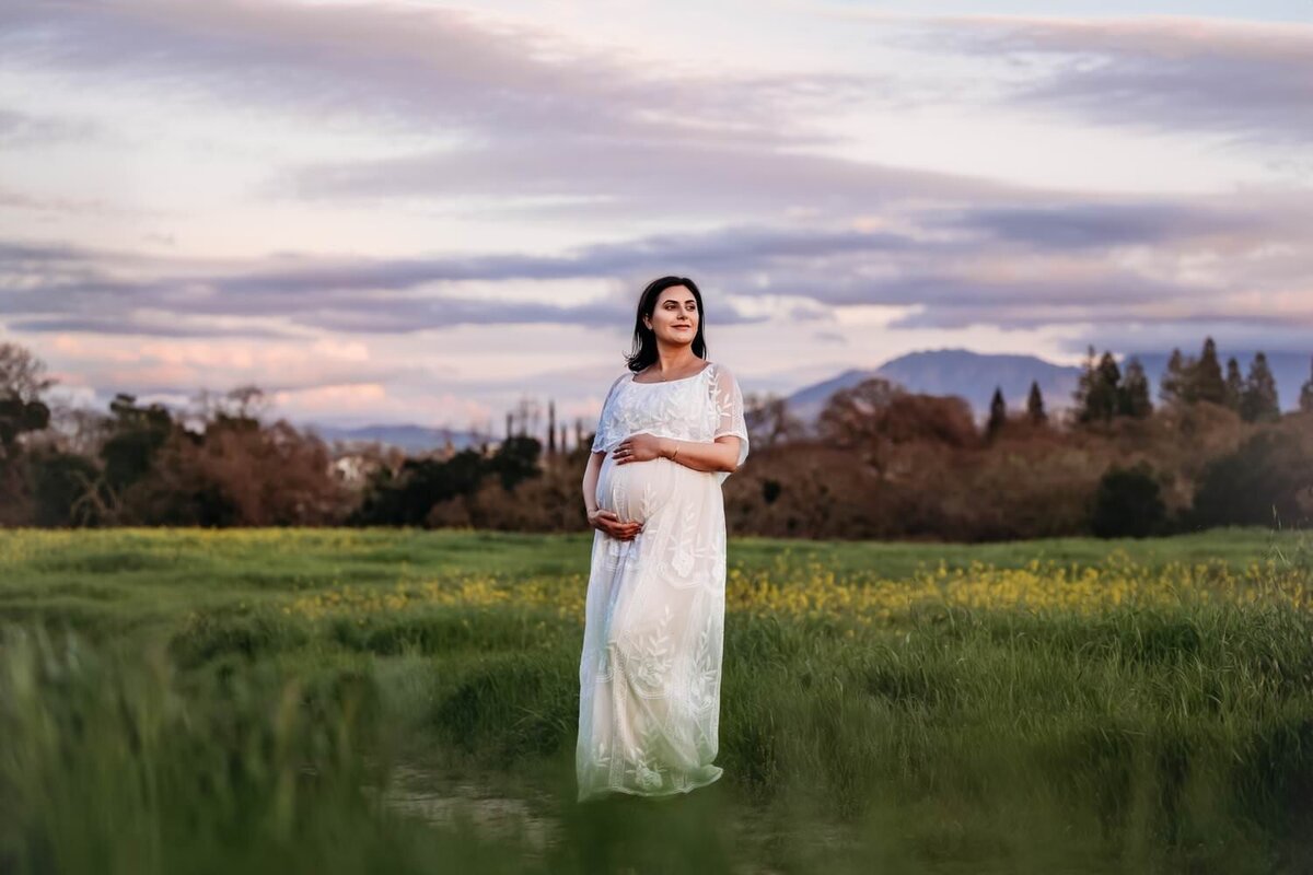 woman in a white maternity dress in a field of green