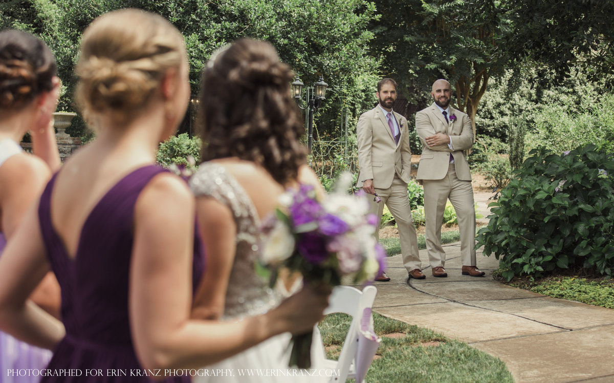 charlotte wedding photographer captures a documentary moment of groom and best man watching bride and bridesmaids from across the garden at Barclay Villa in Raleigh North Carolina