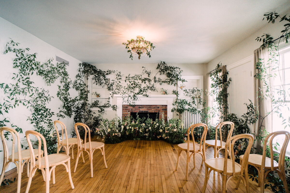 Indoor enchanted garden elopement design with vine-covered walls bentwood chairs & floral nest in front of fireplace at Cornman Farms