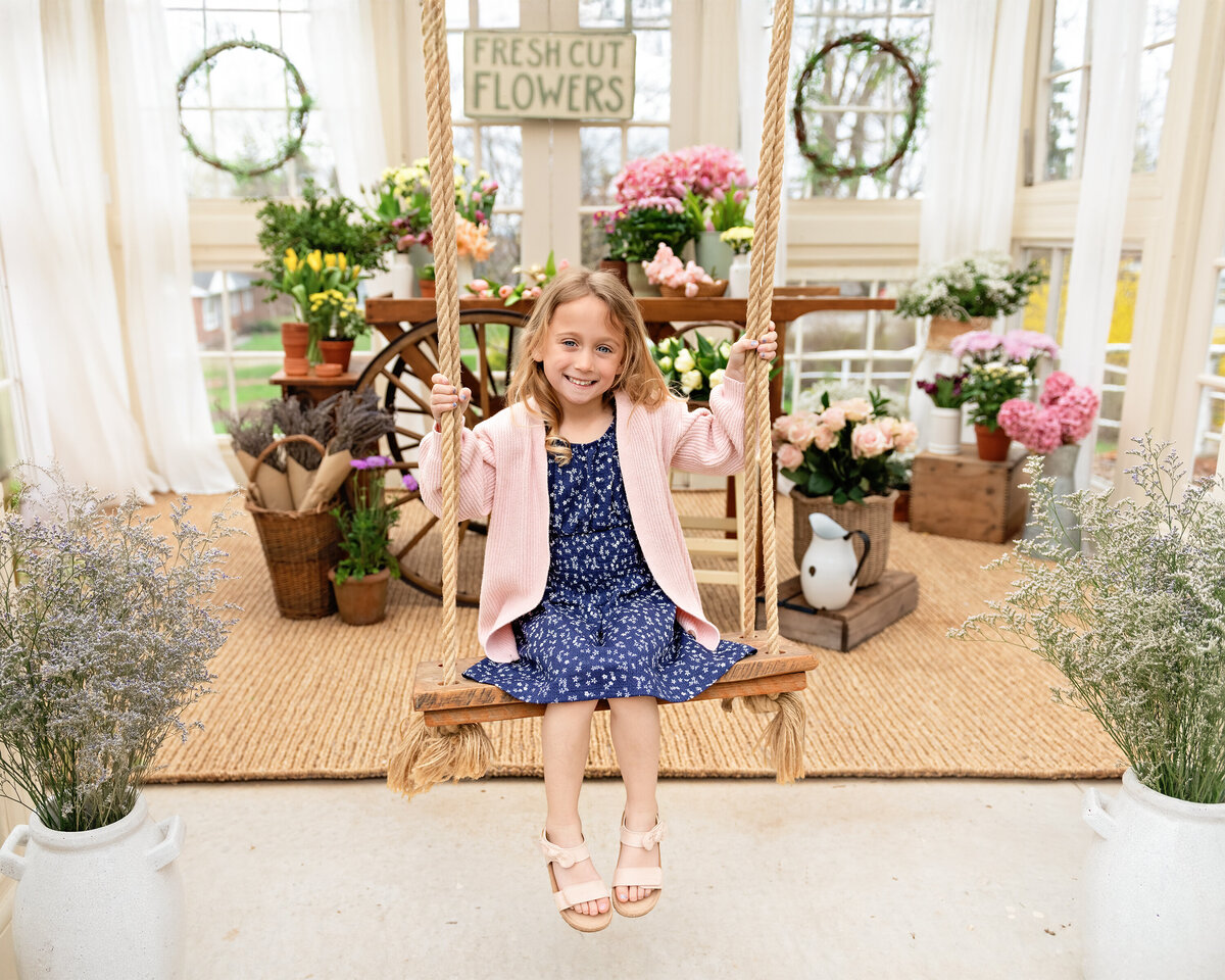 Spring portrait of young girl swinging inside floral greenhouse setup | All Who Wander Flower Farm in Dundas Ontario photographer