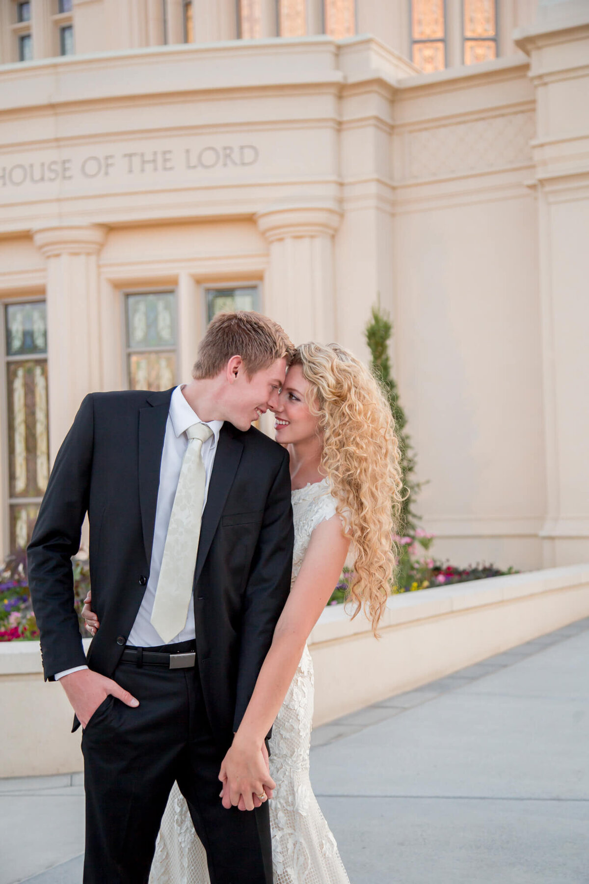 a wedding couple looking at each other in front of a stone building