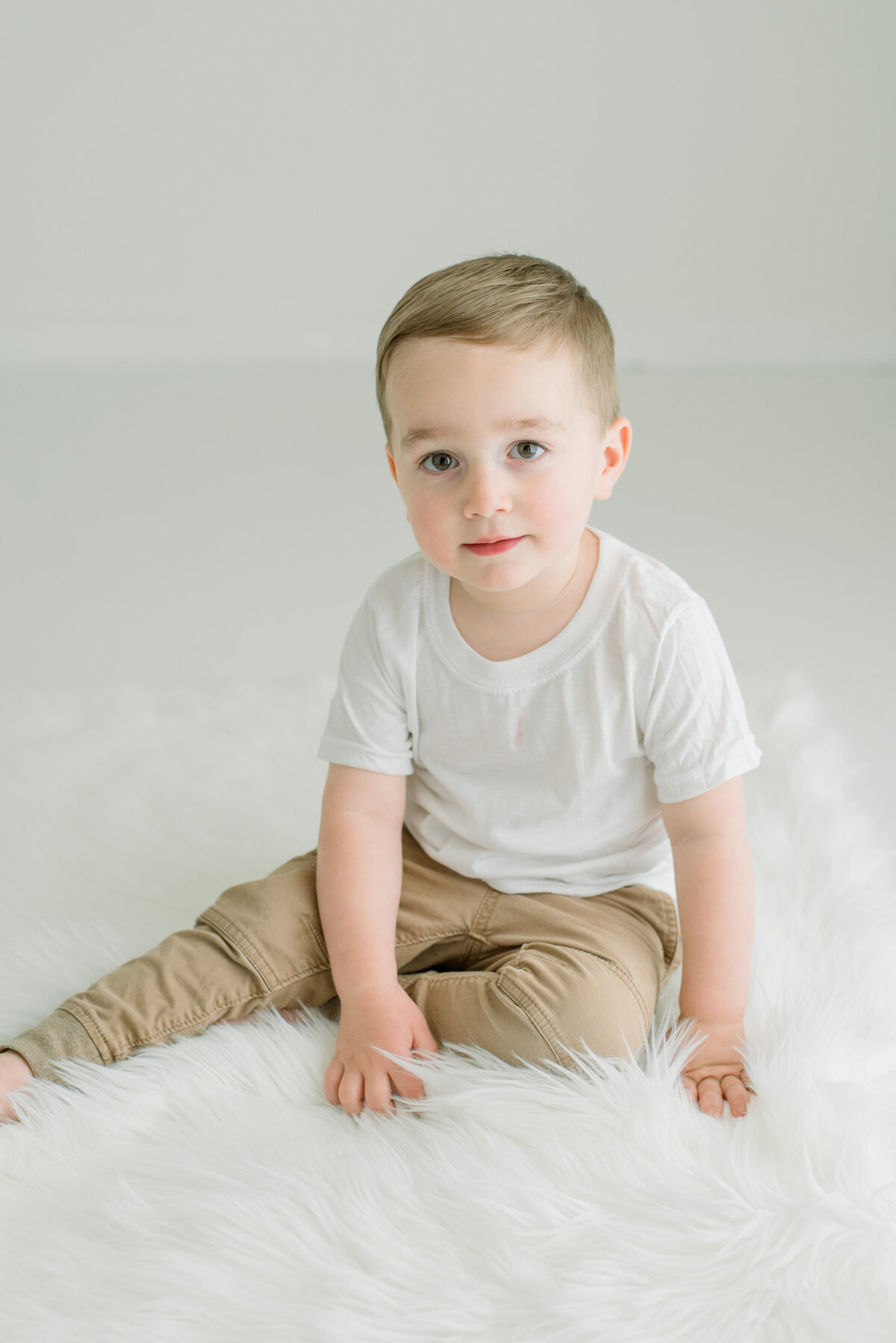 toddler boy sitting on fur rug in studio