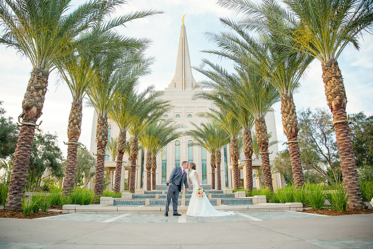 A bride and groom kissing in front of the gilbert lds temple