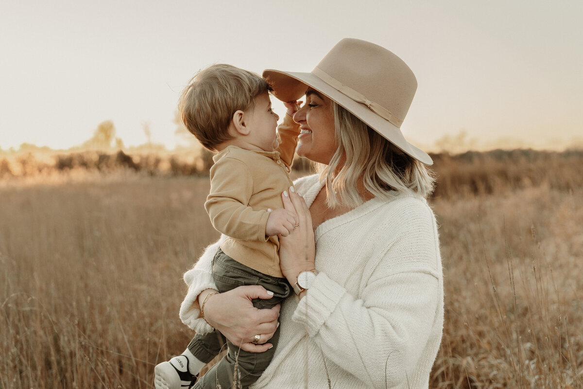 Son trying to take off mom's hat in a field