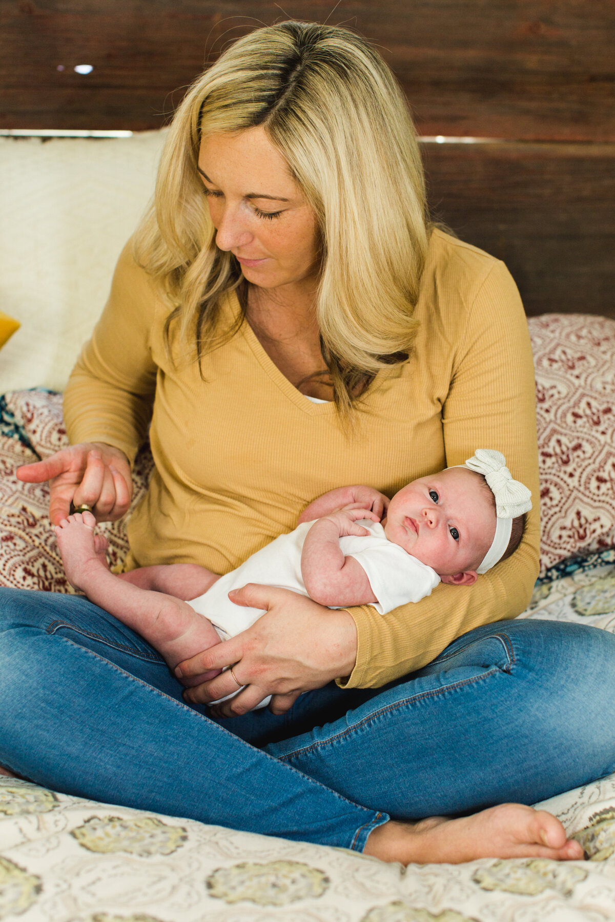 a new mom in a mustard colored tee holds her newborn baby girl in her arms