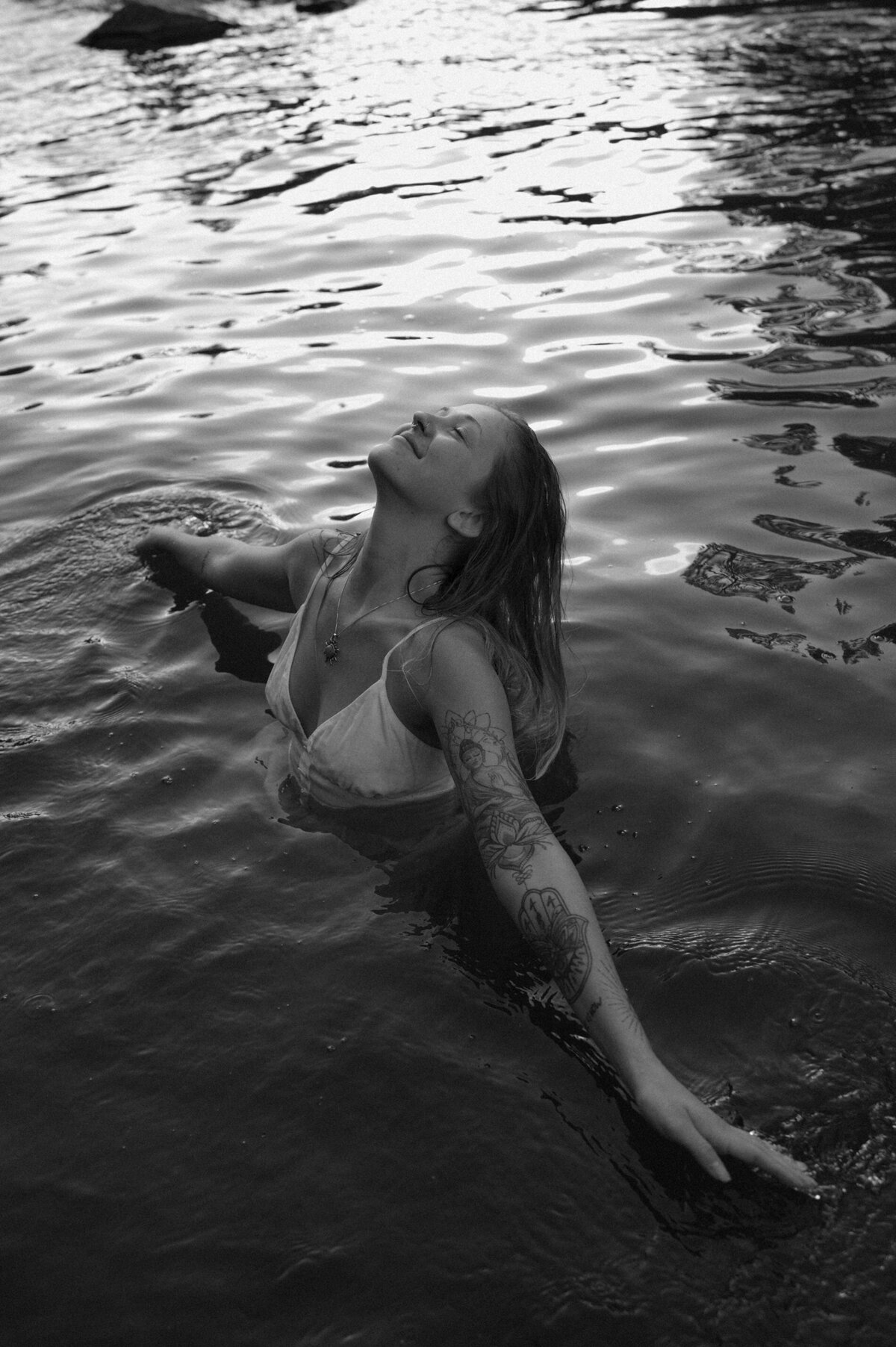 woman with tattoos and long hair takes a swim in the river in Bend, Oregon