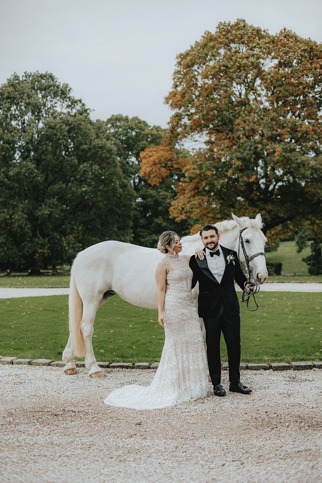 Bride looking at groom holding the reigns of a white horse
