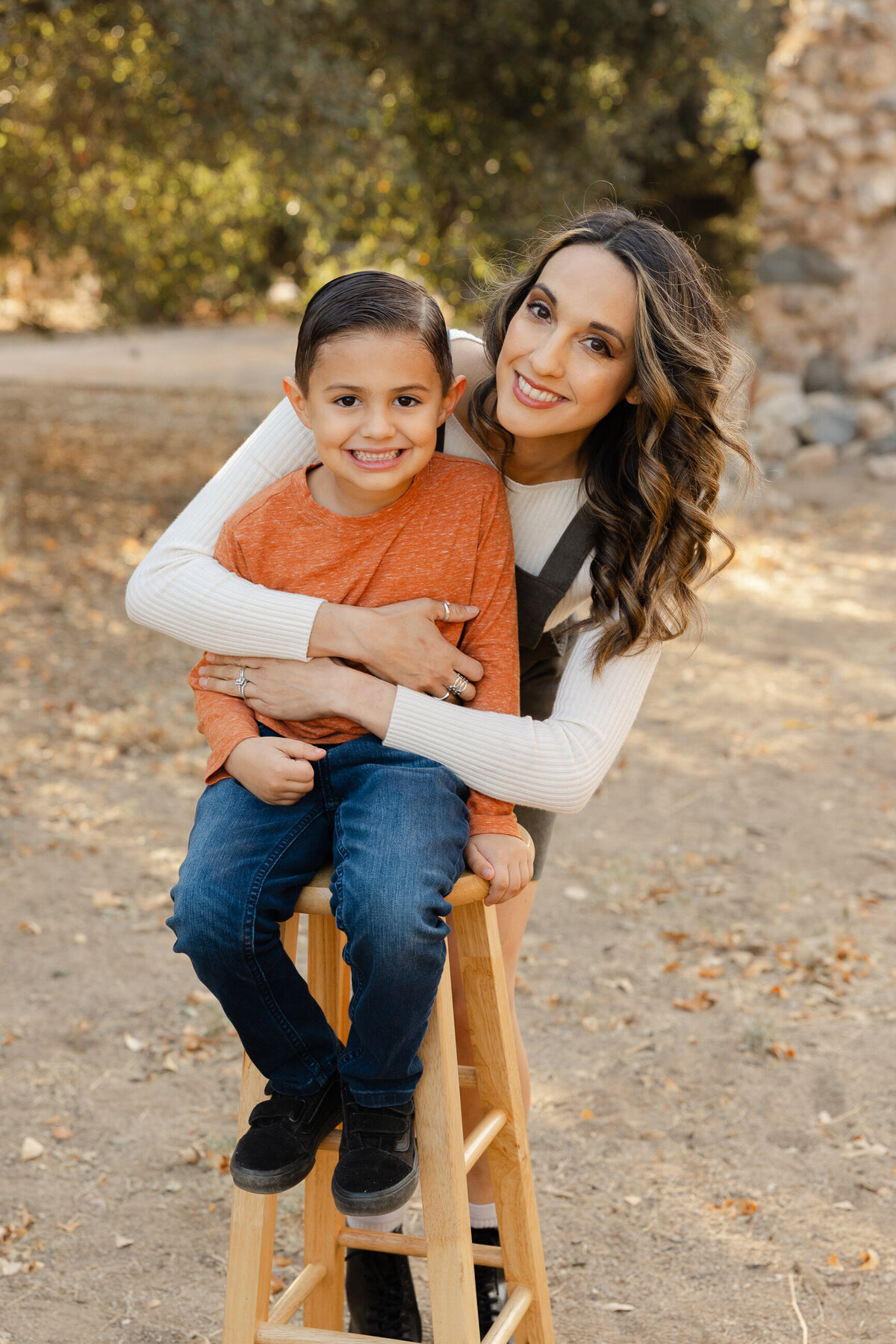 Mother and son smiling together in front of rustic stone backdrop. Photographed by Yucaipa family photographer Kaitlyn Dawn Photography.