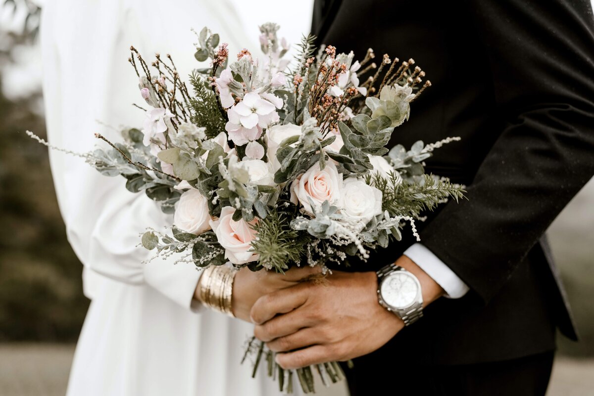 Closeup of wedding bouquet held by a couple