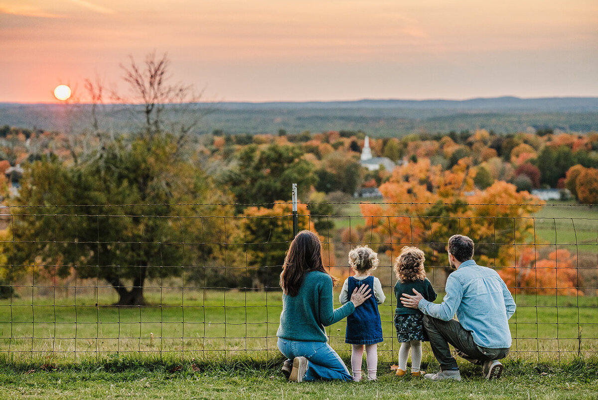 family with twin toddler daughters overlook a valley with fall colors