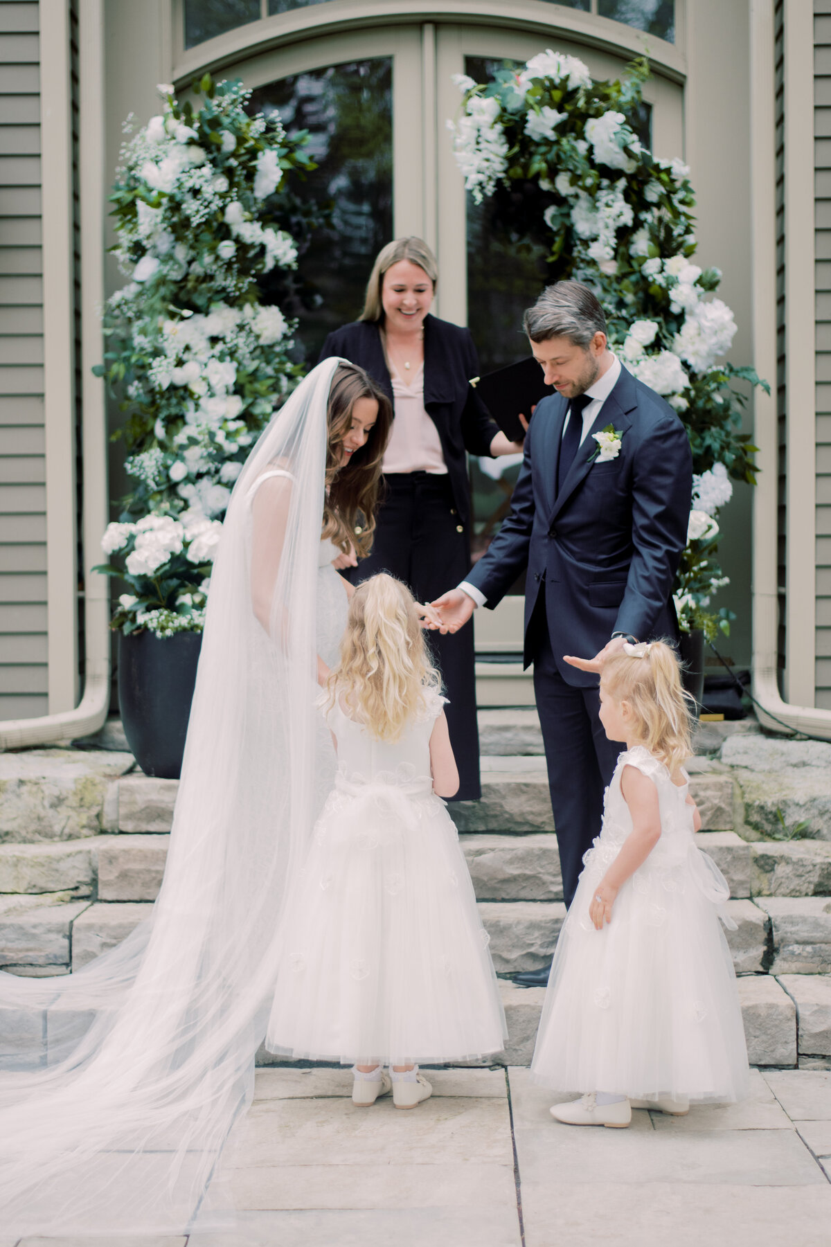 Bride and groom receive wedding bands from flower girls.