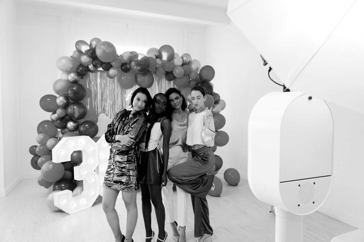 4 women taking a photo with a glam photo booth at a birthday party