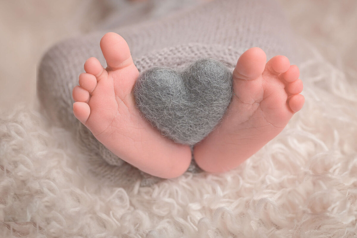 E. Benecki Photography of Bremerton photographs newborn's feet holding a heart during the in home newborn session