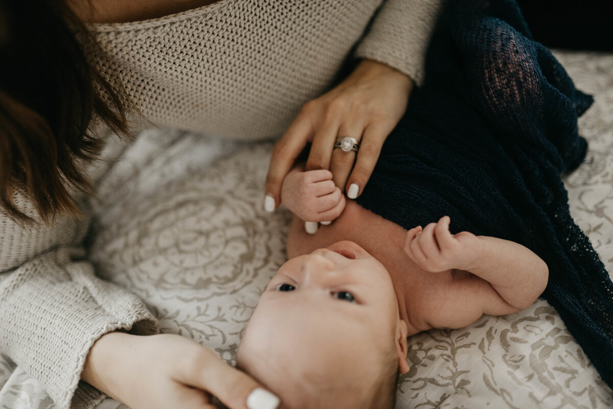 Newborn holds mom's finger