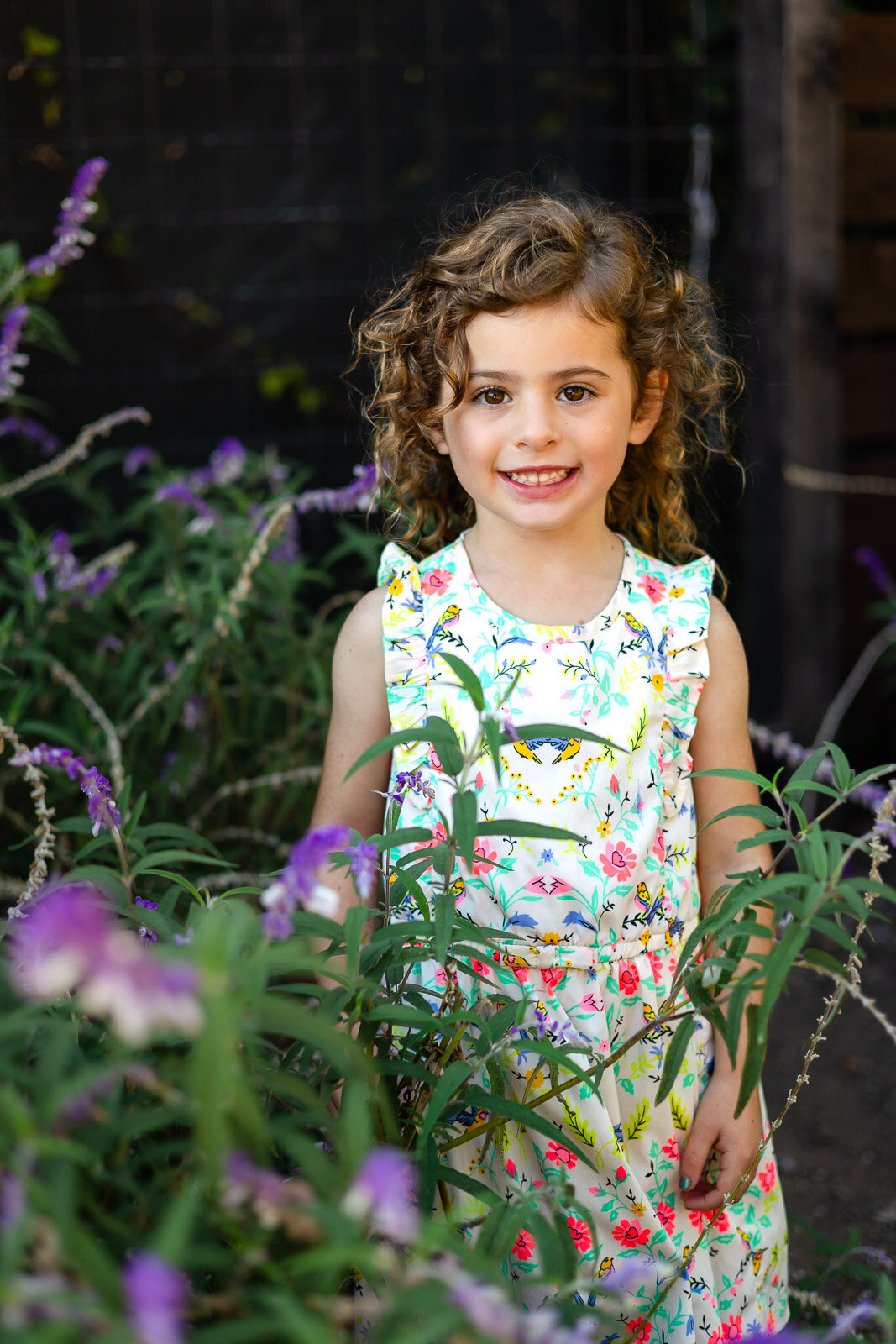 Young girl smiling among purple flowers during Bay Area school photography lifestyle session – Ellobelle Photography