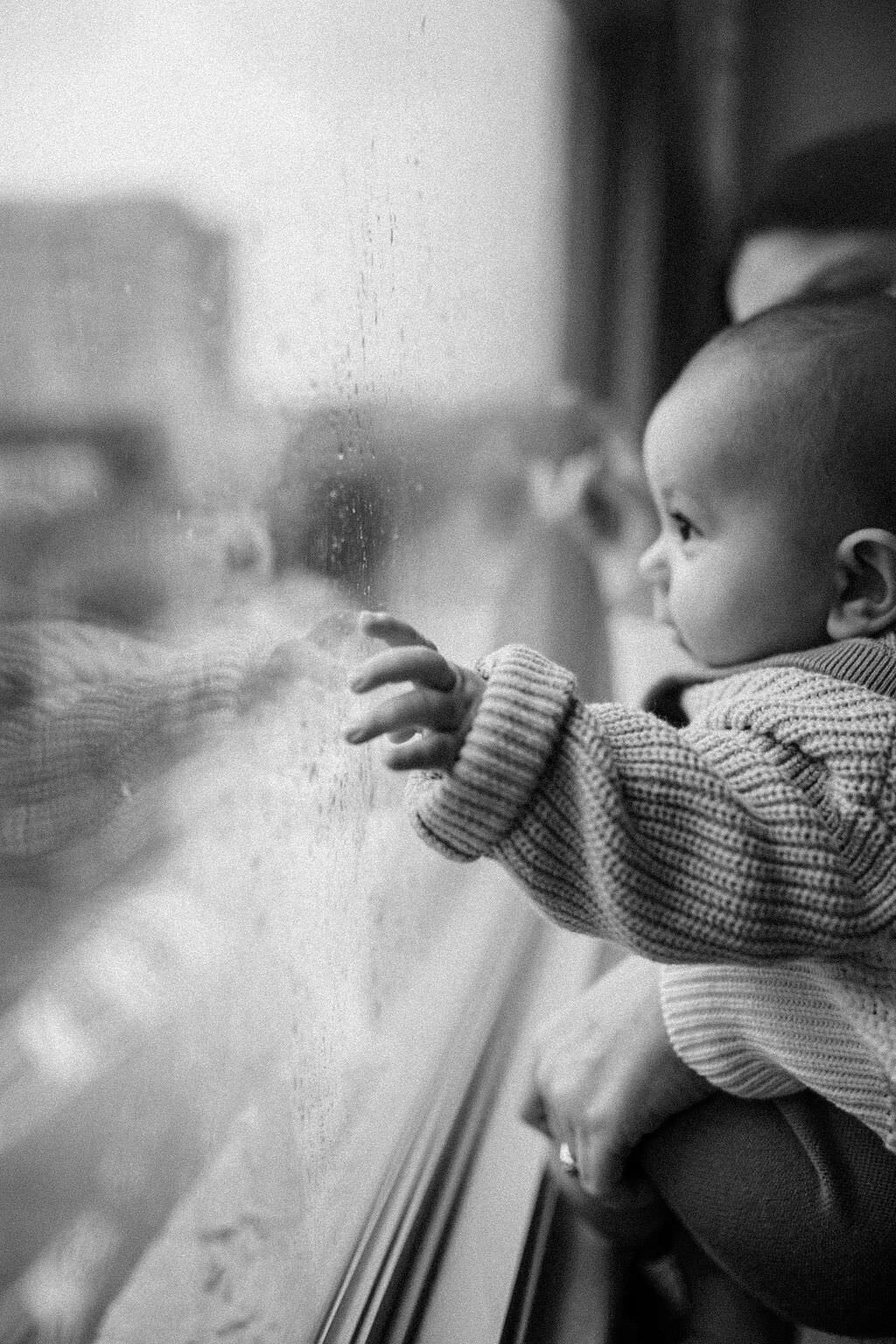 black and white image baby looking out window