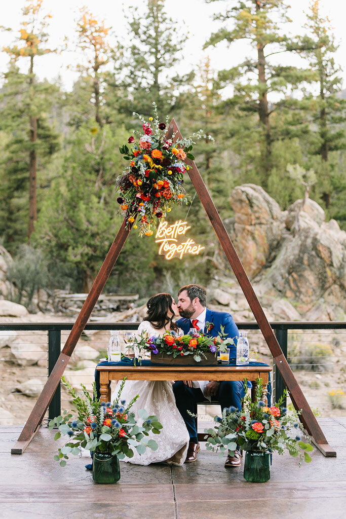 Sweetheart table framed with triangle altar and bright flowers