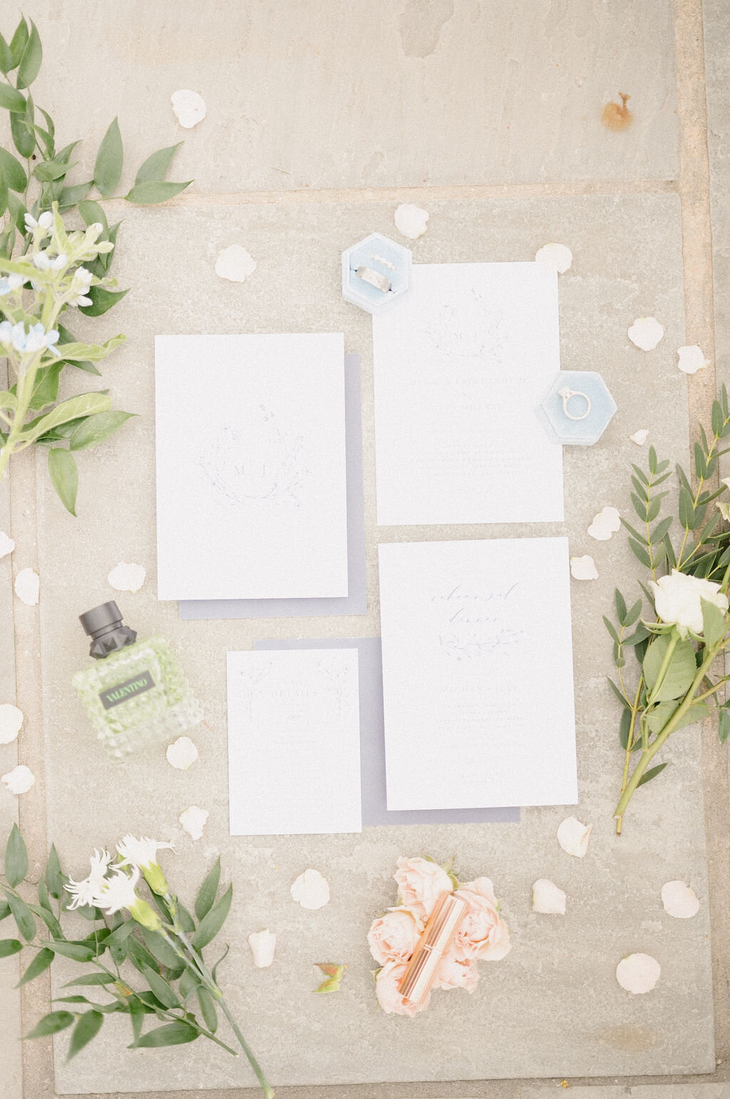 Flay lay of wedding details with greenery and white petals