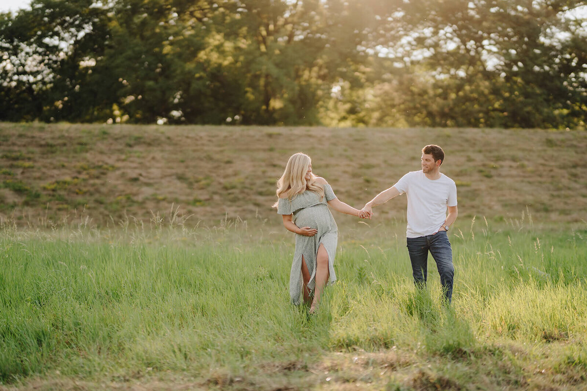 Couple walking along in grassy area for maternity session in Finger Lakes, New York