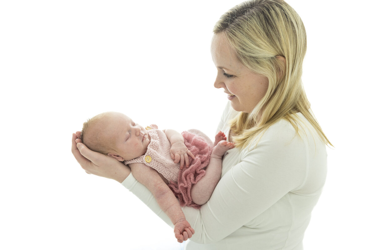 Fotografert i profil; mor står og ser på babyen sin som ligger i armene hennes. Fotografert i Studio Landmark, Fyllingsdalen.