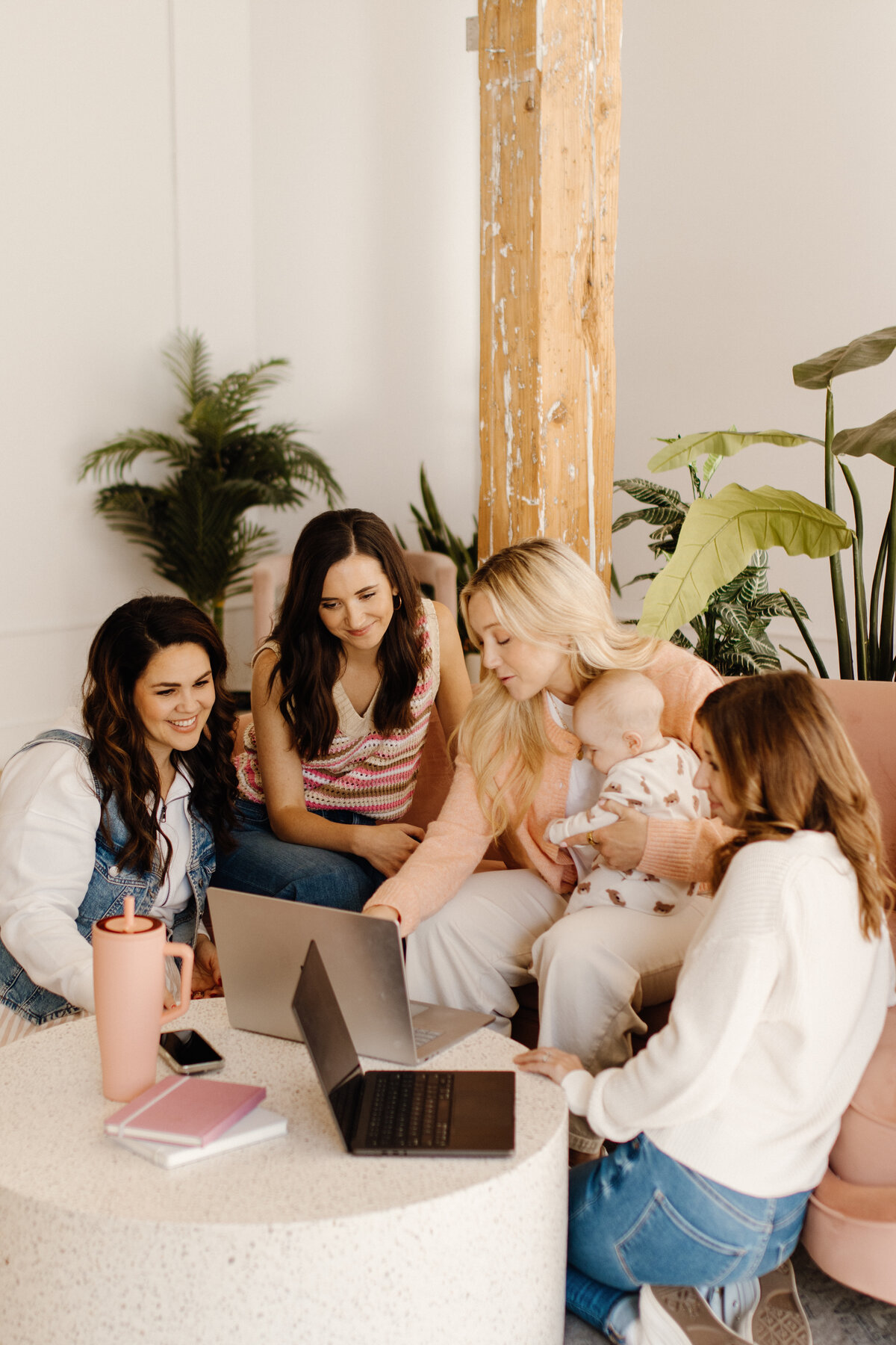 3 women with dark hair on pink couch talking with laptop