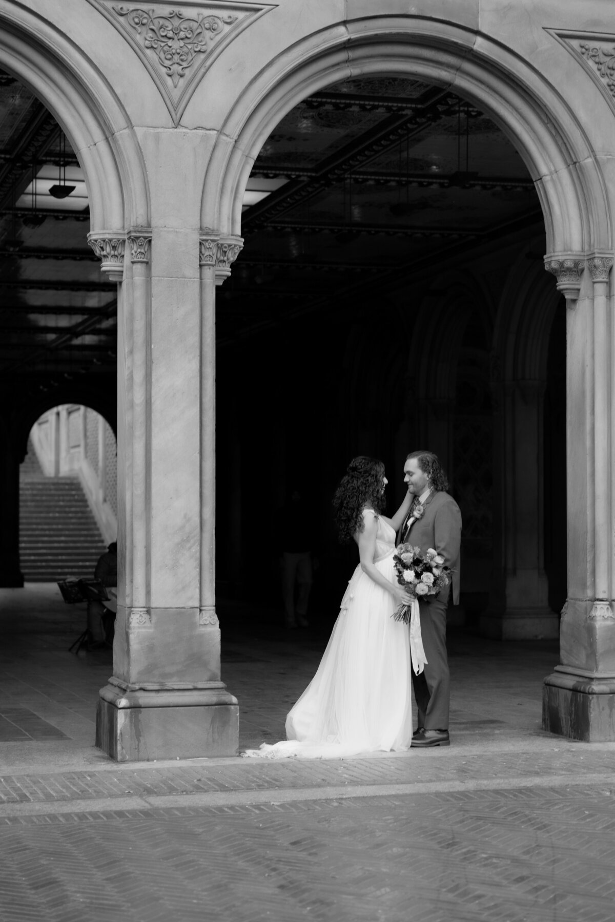 The couple sharing a tender moment beneath Central Park’s beautiful stone arches.