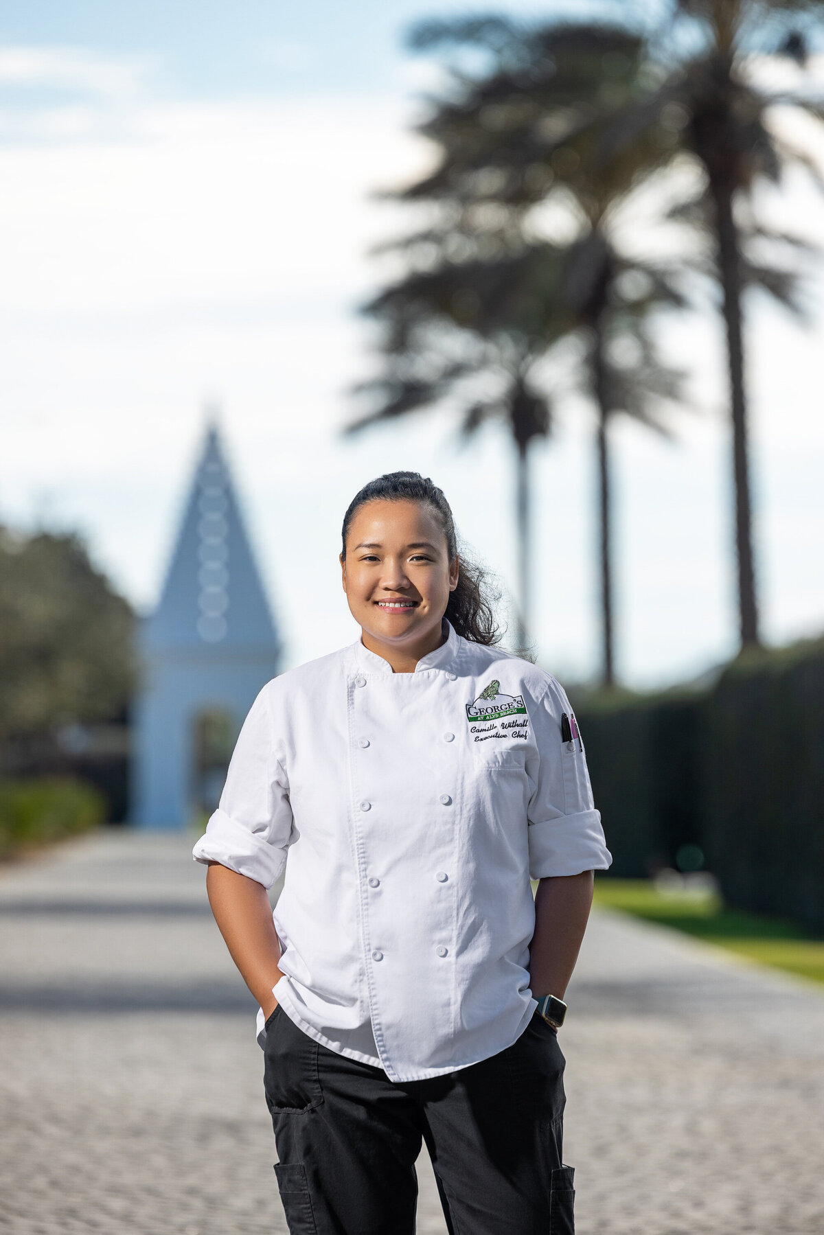 A chef outside with her hands in her pockets