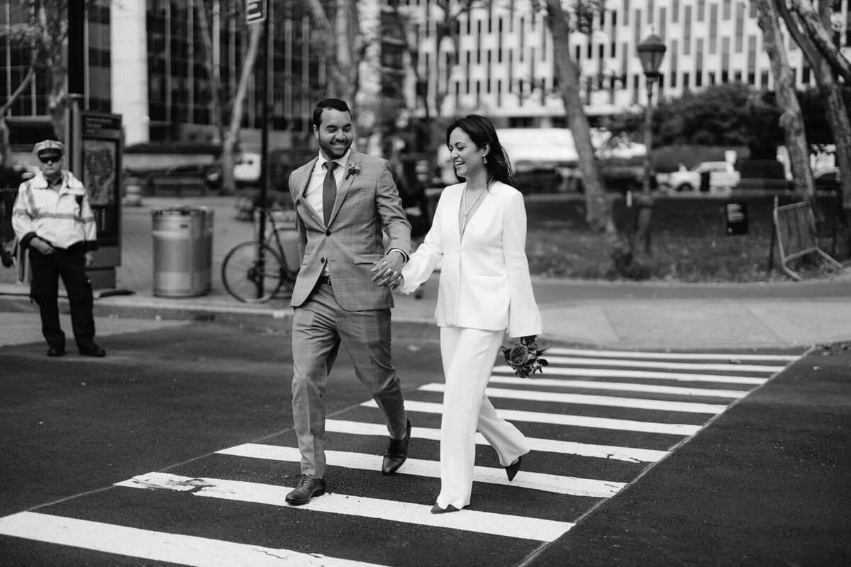 Black and white photo of the bride and the groom crossing the street in New York City. Image by Jenny Fu Studio