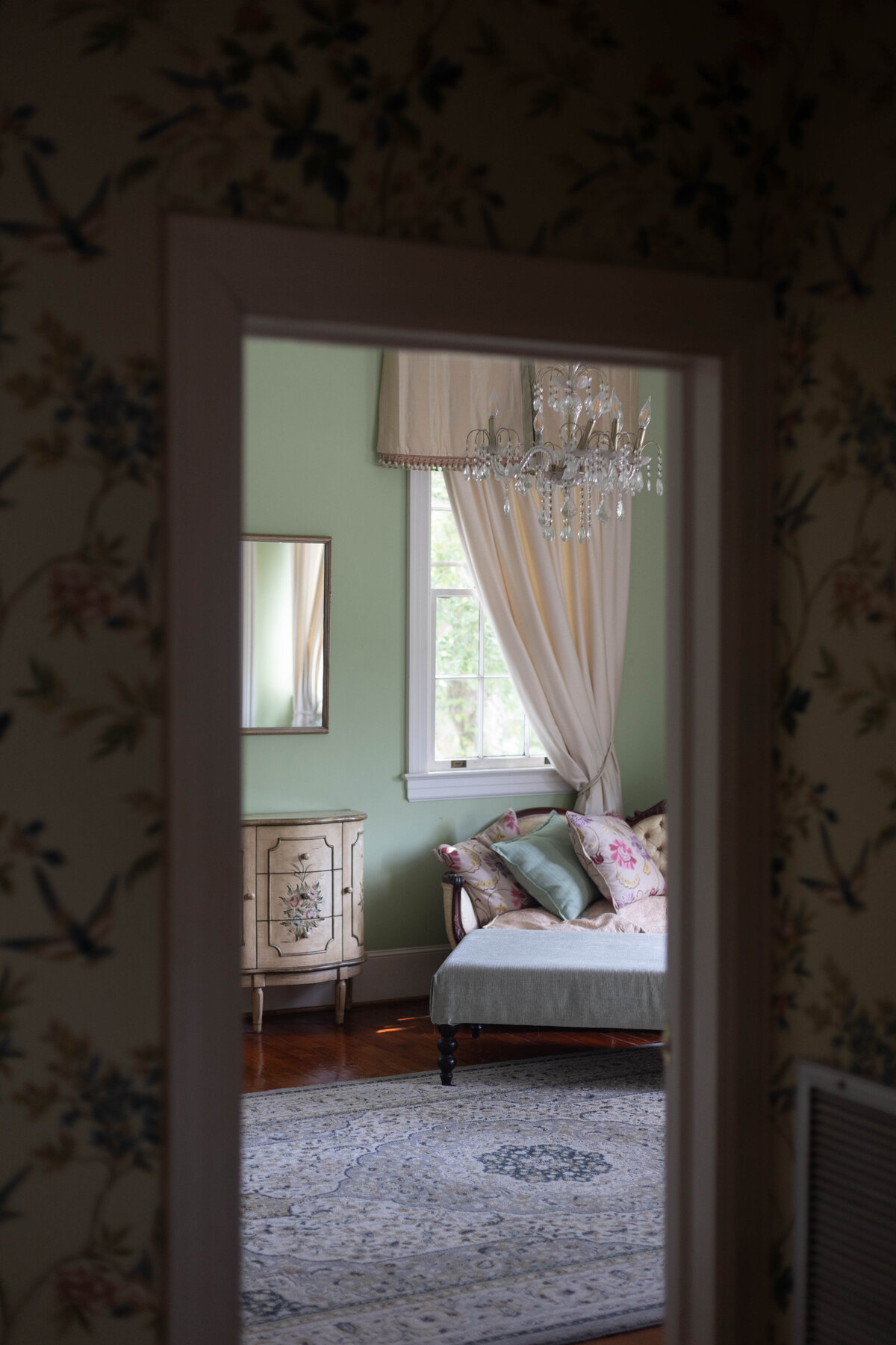 An olive green bedroom with a white couch through a door frame
