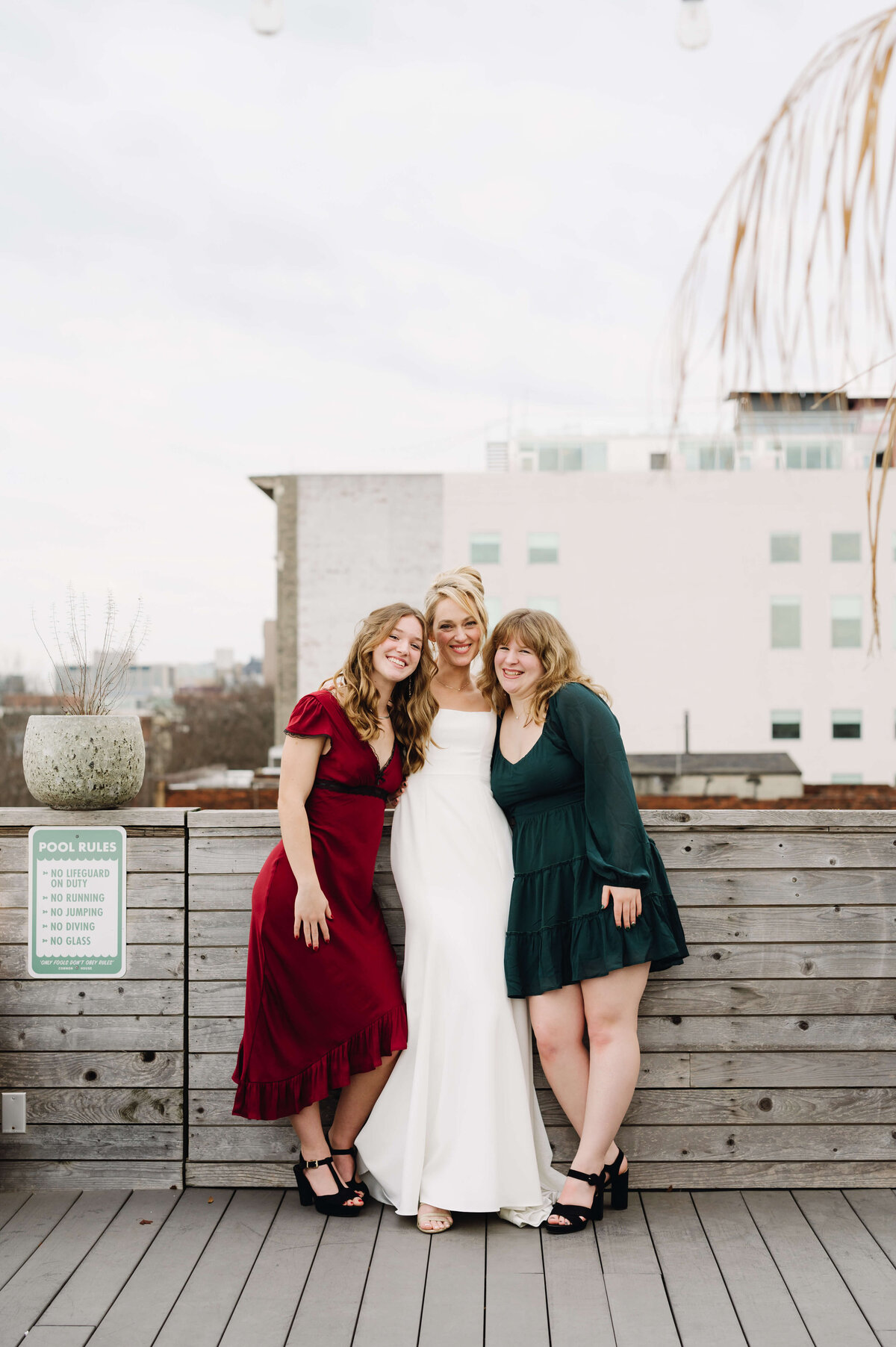 bride and bridesmaids who are in gem tone dresses stand together for wedding portrait
