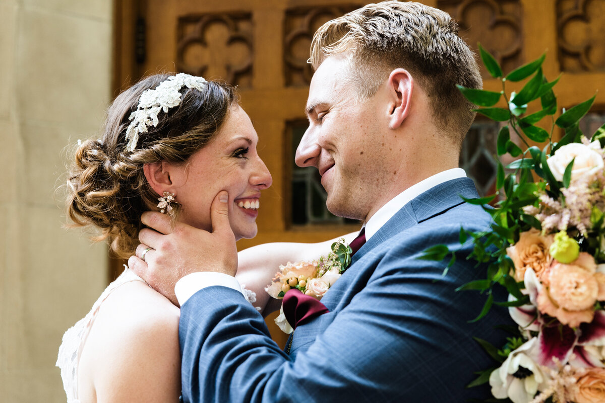 bride and groom look at each other and smile in front of harbison chapel doors