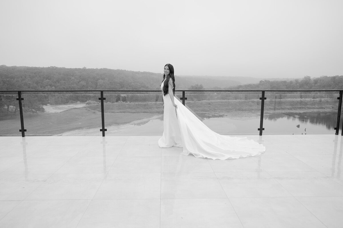 Black and white editorial photo of bride on balcony with gown spread at The Videre Estate in Austin, Texas.