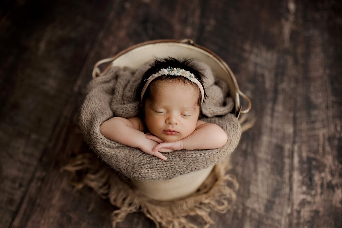 Springville al newborn photography studio baby girl in a bucket on brown with a headband