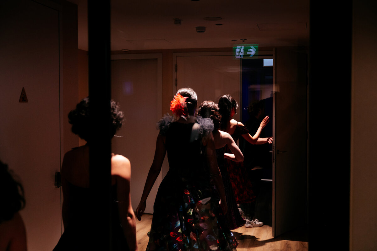 West Side Story performers lopen in een rij backstage naar het podium toe.