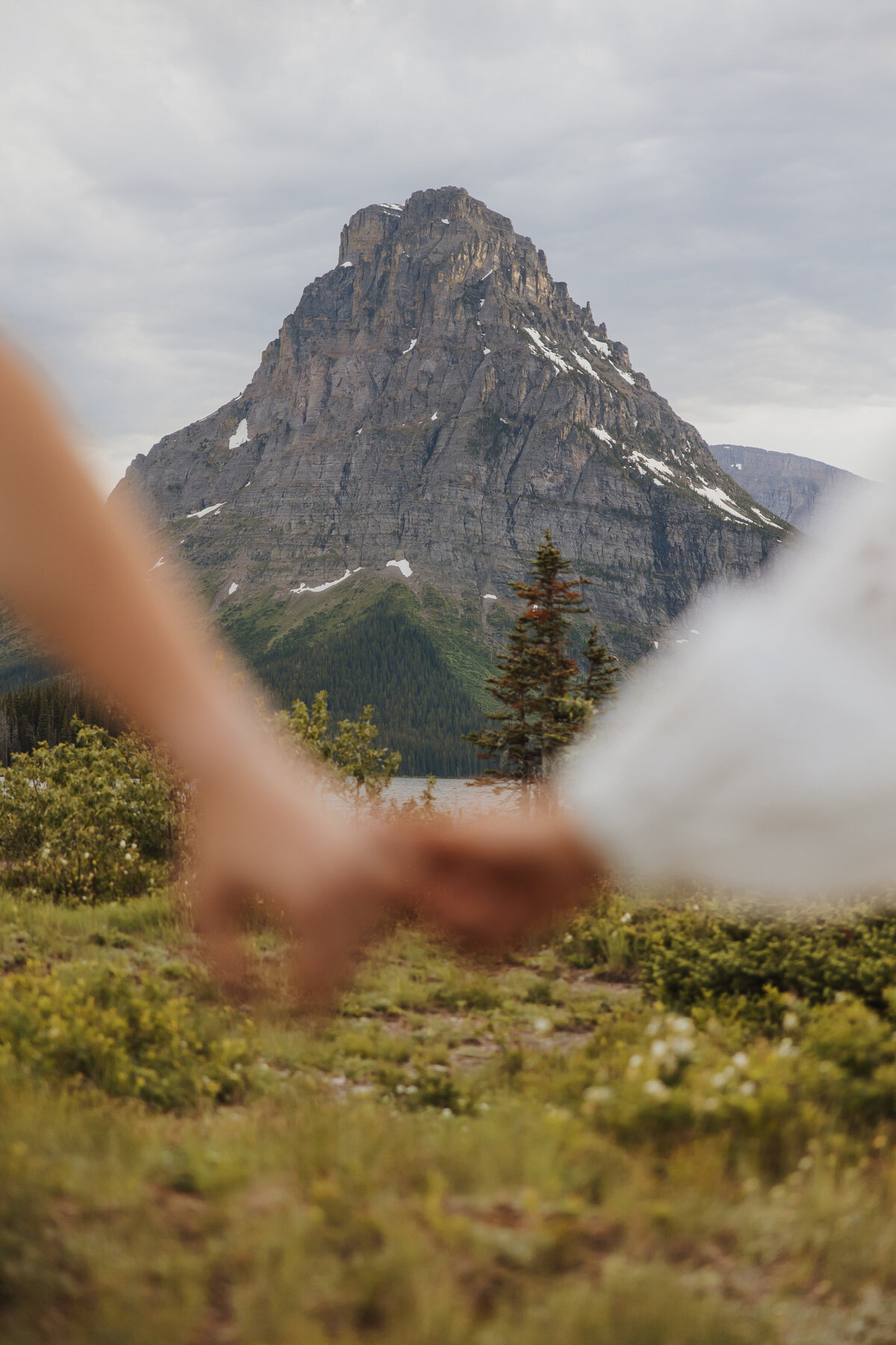 Close-up of bride and groom’s hands with Glacier National Park in the background.