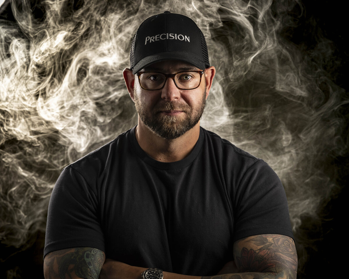 Headshot in CT of man in black shirt and Precision hat, in dramatic smoke-filled studio lighting by Rob Faber Photography.