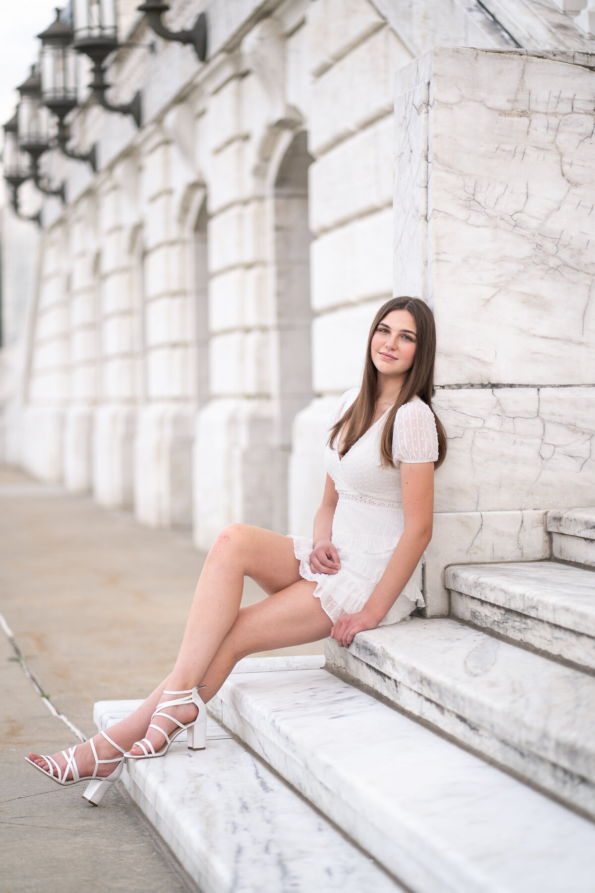 white dress senior girl photoshoot sitting on white staircase, marble building