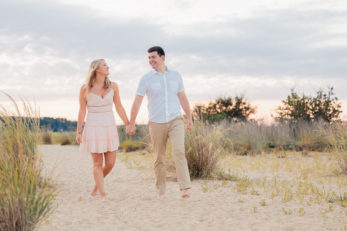 couples walk together on beach after engagement