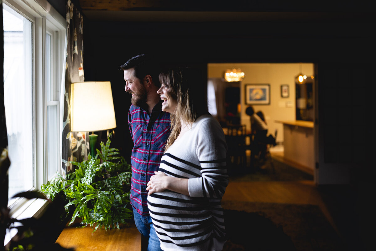 Pregnant mother and partner standing in front of window