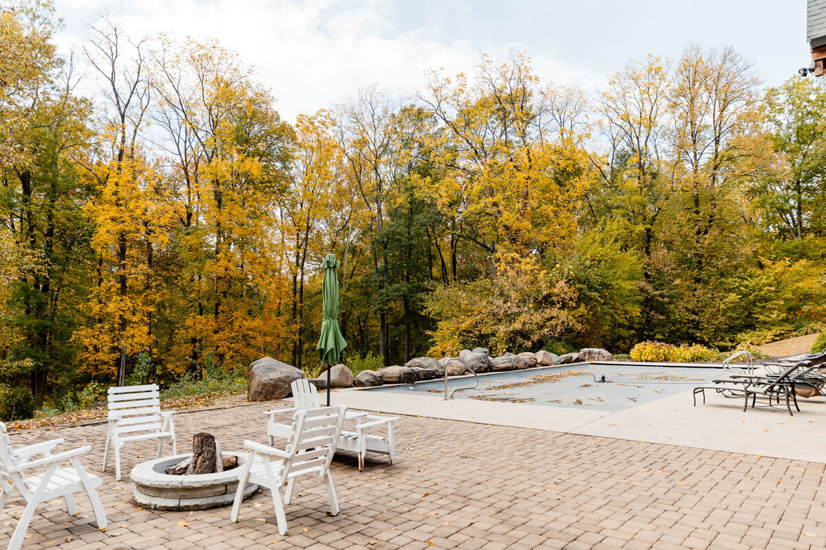 Patio area with fire pit surrounded by autumn trees