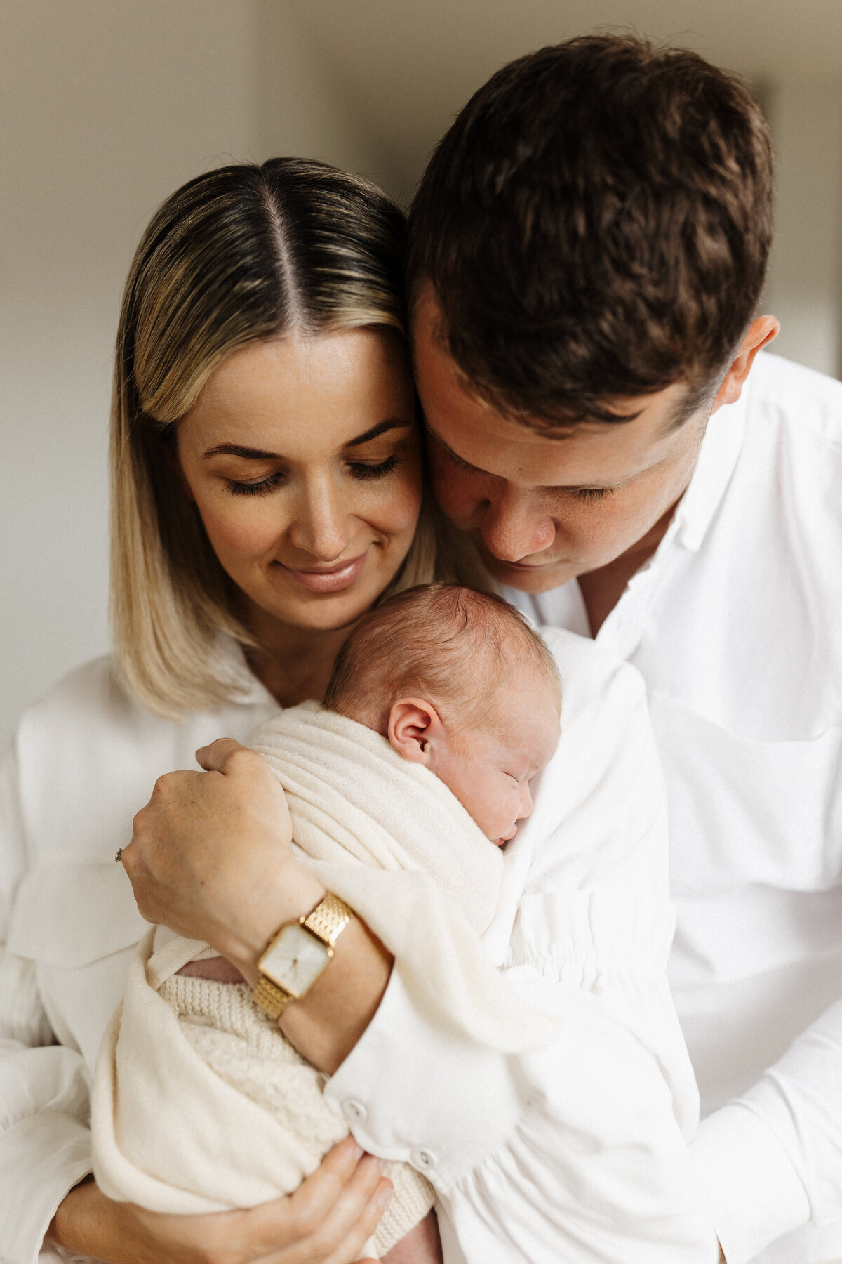 A mother and father holding their newborn baby during a newborn photoshoot in christchurch, a popular pose that is often requested