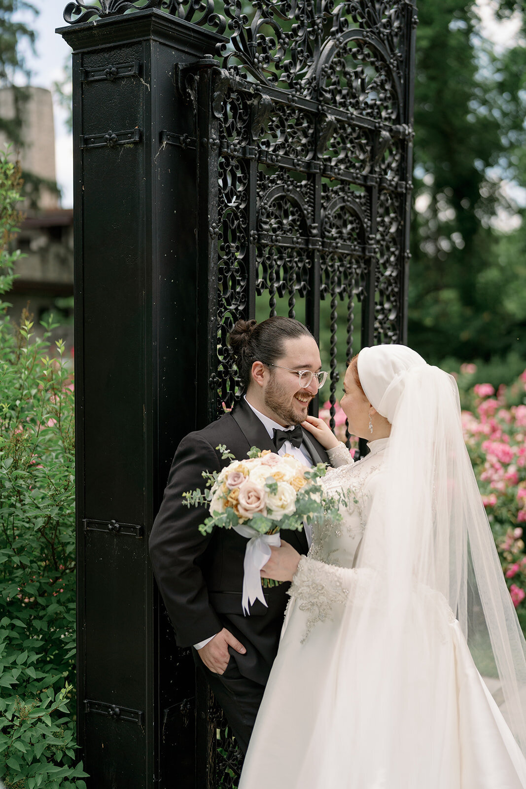 Bride and groom posing by the iconic wrought iron gate at Henry Ford Estate in Dearborn Michigan for timeless wedding photos.