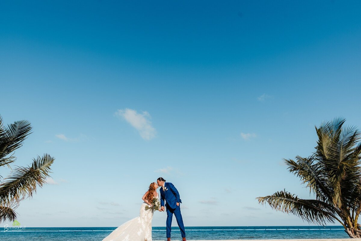 couple kissing on the beach with palm trees on the sides