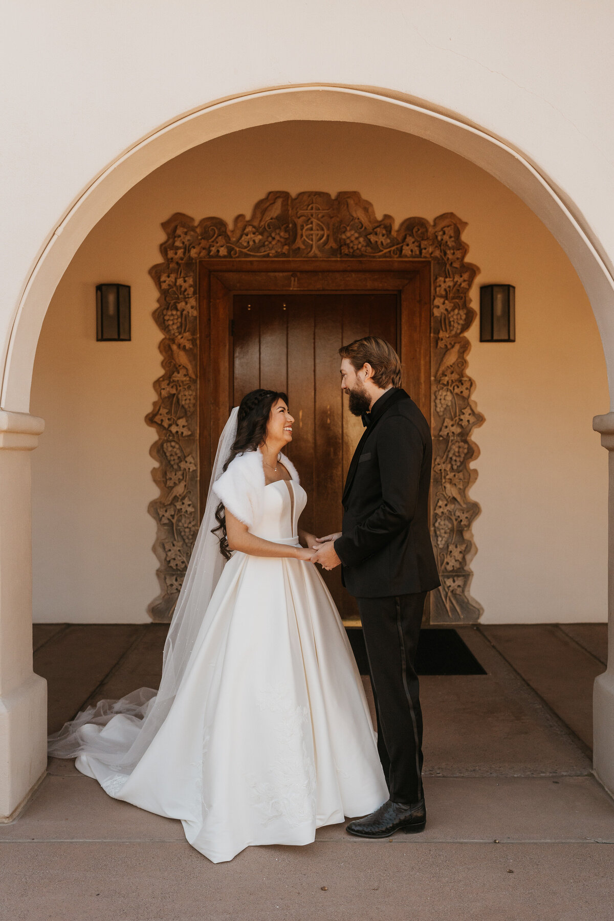 A newlywed couple holding hands and laughing 