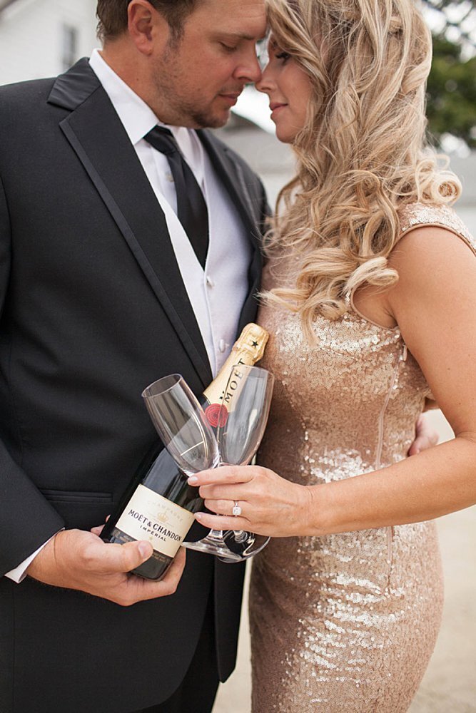Formally-dressed engaged couple holding champagne and glasses